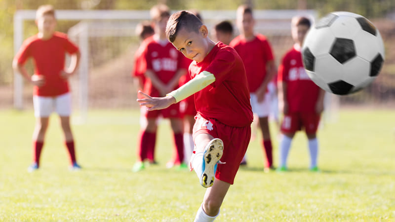 Junge spielt mit Mundschutz Fußball